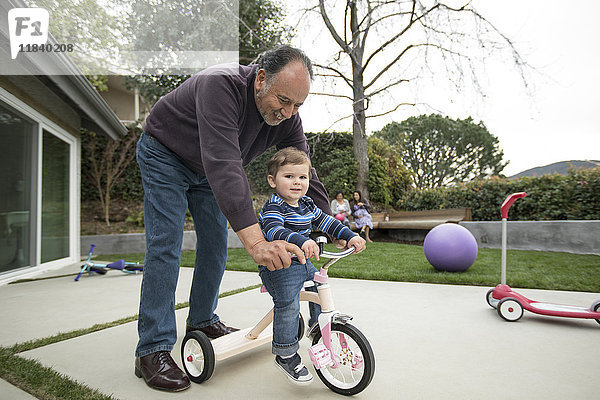 Großvater schiebt Enkel auf Dreirad