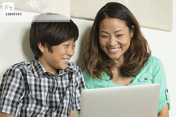 Lächelnde asiatische Mutter und Sohn mit Laptop