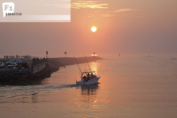 Menschen auf dem Boot und am Ufer bei Sonnenuntergang