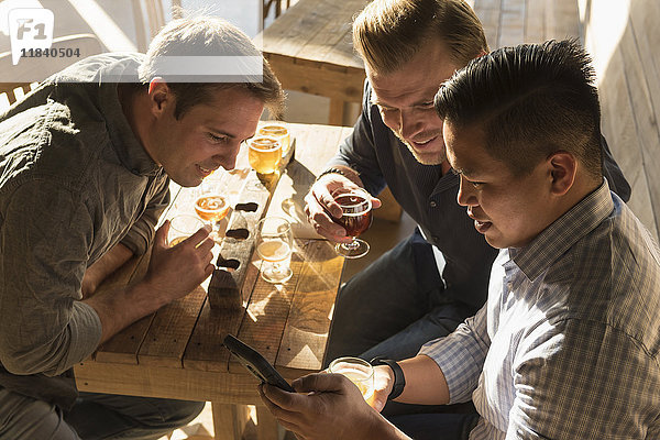 Freunde  die in einer Brauereikneipe mit dem Handy telefonieren