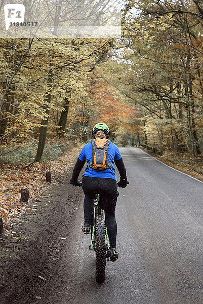 Kaukasische Frau fährt Fahrrad auf einem Waldweg