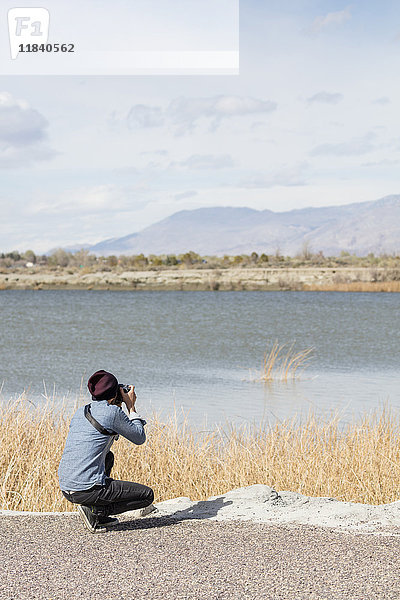 Kaukasische Frau fotografiert Berge am Fluss