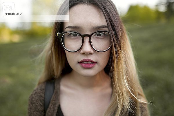 Asiatisches Teenager-Mädchen mit Brille im Feld