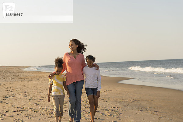 Mutter und Töchter gehen am Strand spazieren