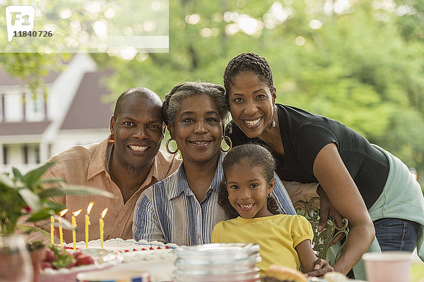 Porträt einer lächelnden Mehrgenerationenfamilie beim Feiern mit Kuchen