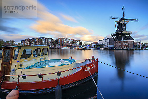 Das Fischerboot umrahmt die Windmühle De Adriaan  die sich in der Abenddämmerung im Fluss Spaarne spiegelt  Haarlem  Nordholland  Niederlande  Europa