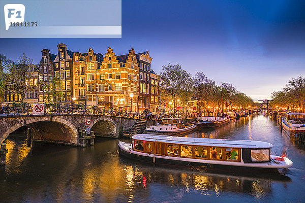 Grachtenlandschaft mit Ausflugsboot in der Abenddämmerung  Amsterdam  Niederlande  Europa