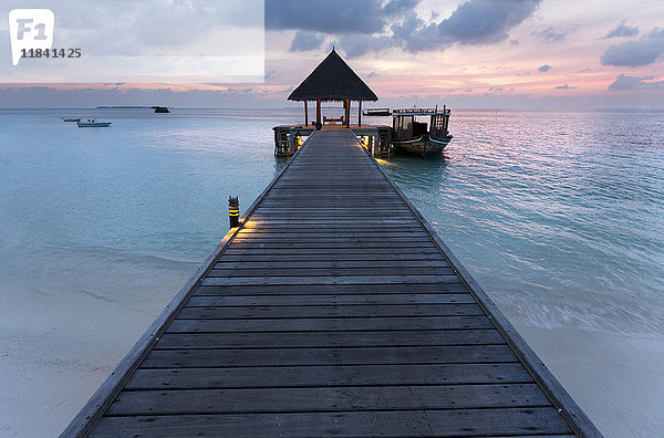 Holzsteg und Boot bei Sonnenuntergang  Coco Palm Resort  Dhuni Kolhu  Baa Atoll  Republik Malediven  Indischer Ozean  Asien