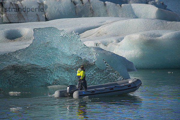 Mann fährt in einem Zodiac zwischen Eisbergen in der Gletscherlagune Jokulsarlon an der Südküste Islands; Island'.