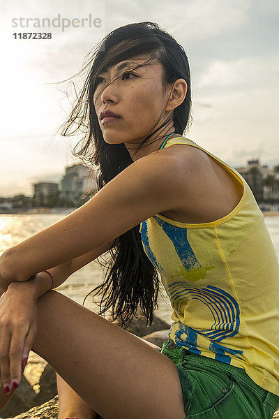 Porträt einer chinesischen jungen Frau  die am Strand von Sitges sitzt; Sitges  Provinz Barcelona  Spanien
