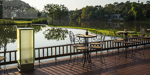 Eine Terrasse mit Stühlen und Tischen mit Blick auf einen ruhigen Fluss; Chiang Rai  Thailand'.