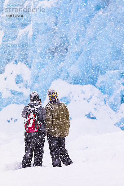 Ein Paar überquert den Portage Lake bei starkem Schneefall im Winter mit Schneeschuhen  um den Endpunkt des Portage Glacier zu sehen  Süd-Zentral-Alaska  USA