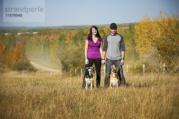 Porträt eines stehenden Paares mit seinen beiden Hunden und einer herbstlichen Landschaft im Hintergrund; Alberta  Kanada'.
