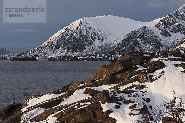 Schroffe  schneebedeckte Berge entlang der Küstenlinie einer Insel; Lofoten  Nordland  Norwegen'.