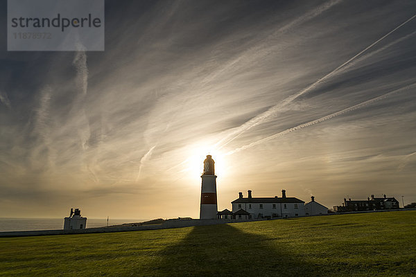 Sonnenlicht hinter einem Leuchtturm wirft einen Schatten auf ein Grasfeld an der Küste; South Shields  Tyne and Wear  England'.
