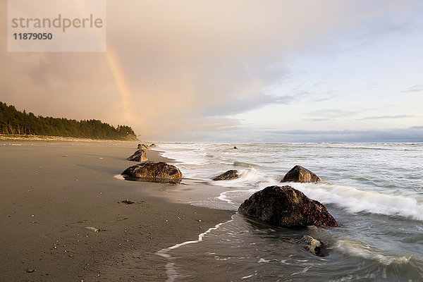 Ein Regenbogen leuchtet in Gewitterwolken über einem Strand und einer Küste; Alaska  Vereinigte Staaten von Amerika'.