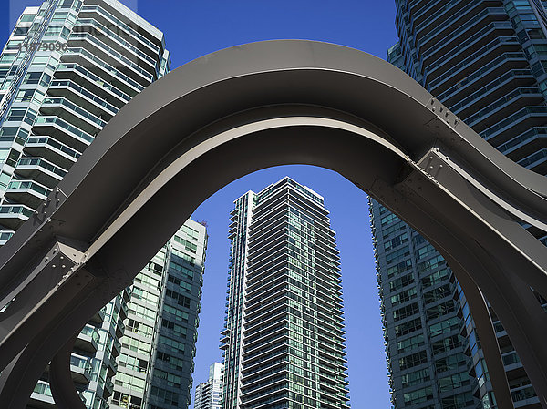 Ein Stahlbogen im Vordergrund mit Wohnhochhäusern vor einem blauen Himmel im Hintergrund; Toronto  Ontario  Kanada