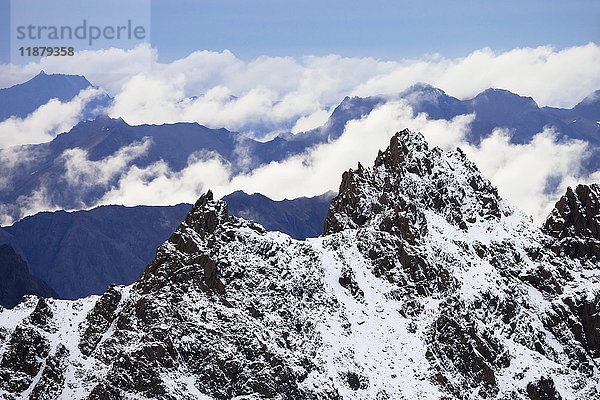 Schroffe  schneebedeckte Gipfel der Kenai Mountains mit blauem Himmel und Wolken; Alaska  Vereinigte Staaten von Amerika'.
