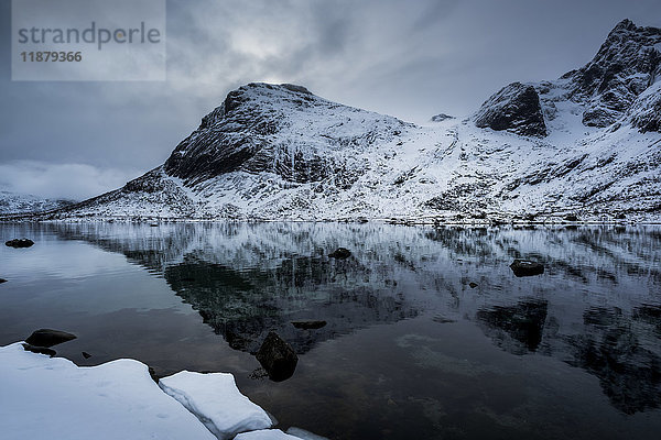 Landschaft mit zerklüfteten  schneebedeckten Bergen  die sich im ruhigen Meerwasser spiegeln; Lofoton-Inseln  Nordland  Norwegen'.