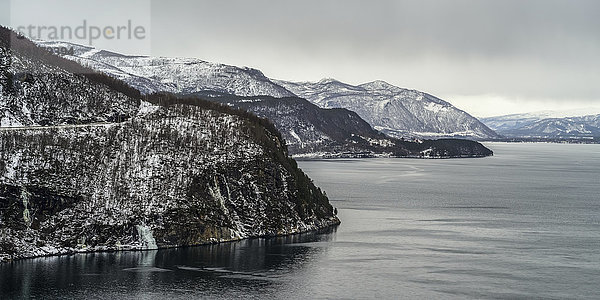 Die zerklüftete Küste und das ruhige Meerwasser unter einem wolkenverhangenen Himmel; Nordland  Norwegen'.