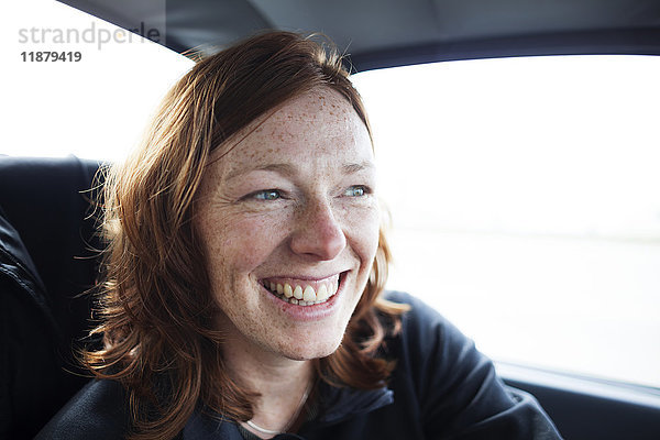 Eine Frau mit roten Haaren und Sommersprossen lächelt  während sie in einem Auto fährt; Alaska  Vereinigte Staaten von Amerika'.