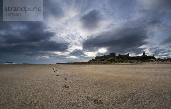 Eine einzelne Reihe von Fußabdrücken am Strand mit Bamburgh Castle im Hintergrund; Bamburgh  Northumberland  England'.