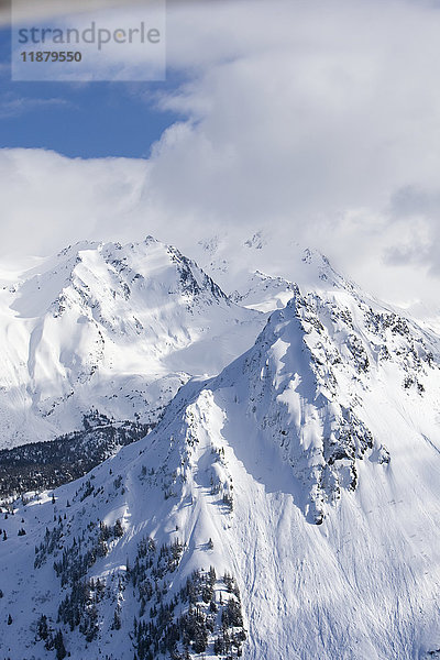 Schneebedeckte Kenai Mountains mit blauem Himmel  der aus den Wolken herausragt  Kachemak Bay State Park; Alaska  Vereinigte Staaten von Amerika'.