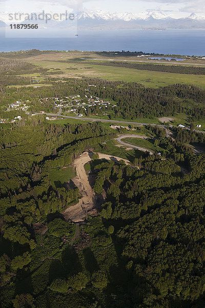 Eine kurvenreiche Straße durch einen Wald im Vordergrund mit Blick auf die Kenai Mountains und die Kachemak Bay im Hintergrund; Homer  Alaska  Vereinigte Staaten von Amerika'.