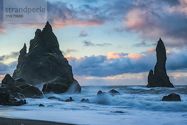 Die als Reynisdrangar bekannten Meeresstapel mit Wellen und Sonnenaufgang über ihnen  Südküste; Island'