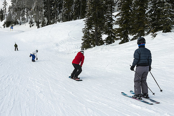 Eine Gruppe von Skifahrern und Snowboardern  die einen Hügel hinunterfahren; Whistler  British Columbia  Kanada'.