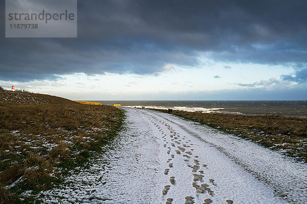 Fußspuren im Schnee auf einem Weg  der zum Horizont führt; South Shields  Tyne and Wear  England'.