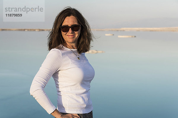 Porträt einer Frau  die eine Sonnenbrille trägt und mit dem Toten Meer im Hintergrund steht; South District  Israel'.