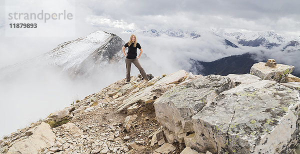 Eine Wanderin posiert allein für ein abenteuerliches Porträt auf dem Gipfel eines Berges auf den Wanderwegen des Kicking Horse Mountain in den Rocky Mountains; British Columbia  Kanada'.