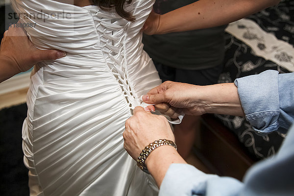 Eine Frau hilft einer Braut an ihrem Hochzeitstag beim Ankleiden; Ontario  Kanada'.