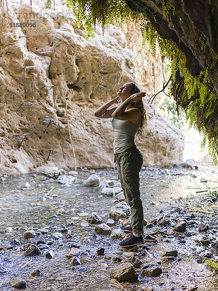 Eine junge Frau steht auf einem Felsen und blickt entlang eines Baches in der Dodim-Höhle  Naturreservat Ein Gedi; Süddistrikt  Israel'.