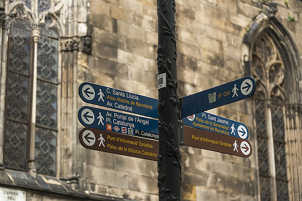 Zielschilder für Sehenswürdigkeiten an einem Pfosten mit einer alten Steinmauer und Fenstern im Hintergrund  Gotisches Viertel; Barcelona  Katalonien  Spanien'.