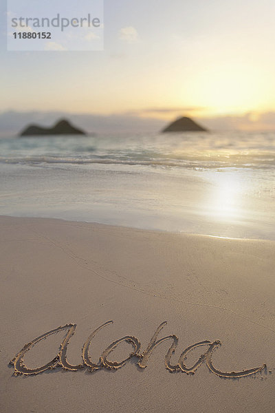 Aloha geschrieben auf dem Sand am Lanikai Beach in Kailua mit den Mokulua Zwillingsinseln im Hintergrund bei Sonnenaufgang; Honolulu  Oahu  Hawaii  Vereinigte Staaten von Amerika'.