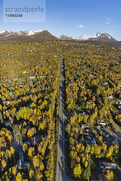 Luftaufnahme der Häuser am Hang in Anchorage  Schnee auf den Gipfeln der Chugach Mountains im Hintergrund  herbstlich gefärbte Bäume in der Stadt  Süd-Zentral-Alaska; Alaska  Vereinigte Staaten von Amerika'.