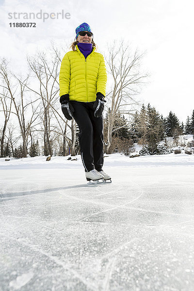 Tiefblick auf eine Frau  die auf einem zugefrorenen Teich Schlittschuh läuft; Calgary  Alberta  Kanada'.