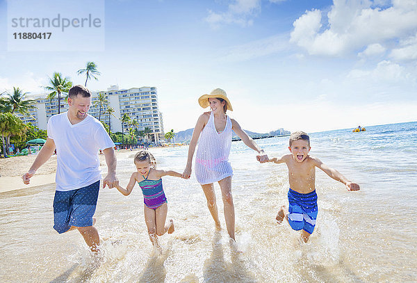 Eine vierköpfige Familie genießt einen Sommerurlaub am Waikiki Beach; Honolulu  Oahu  Hawaii  Vereinigte Staaten von Amerika'.