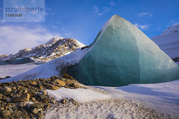 Ein Stück Gletschereis ragt aus der felsigen  schneebedeckten Moräne des Black Rapids Glacier im Winter heraus; Alaska  Vereinigte Staaten von Amerika'.