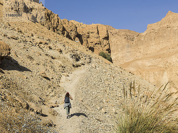 Eine junge Frau wandert auf einem Pfad durch die zerklüftete Hügellandschaft des Naturreservats Ein Gedi  Bezirk Totes Meer; Region Süd  Israel '