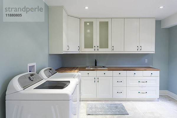 Eine neue Wohnwaschküche mit weißen Schränken und blauen Wänden; Grimsby  Ontario  Kanada'.