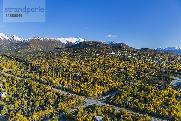 Luftaufnahme der Häuser am Hang in Anchorage  Schnee auf den Gipfeln der Chugach Mountains im Hintergrund  herbstlich gefärbte Bäume in der Stadt  Süd-Zentral-Alaska; Alaska  Vereinigte Staaten von Amerika'.