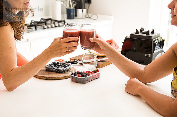 Freunde stoßen mit Smoothies an