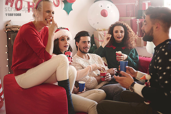 Junge Frauen und Männer essen auf der Weihnachtsfeier Popcorn auf dem Sofa