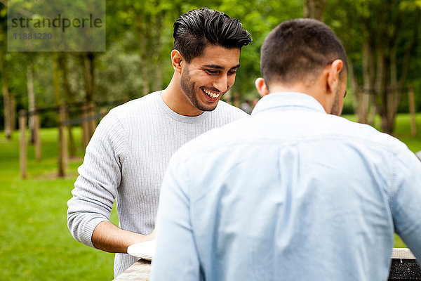 Mann beim Grillen mit Freund im Park