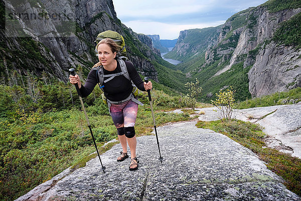 Mittlere erwachsene Frau beim Wandern durch ein felsiges Tal  Gros Morne National Park  Neufundland  Kanada