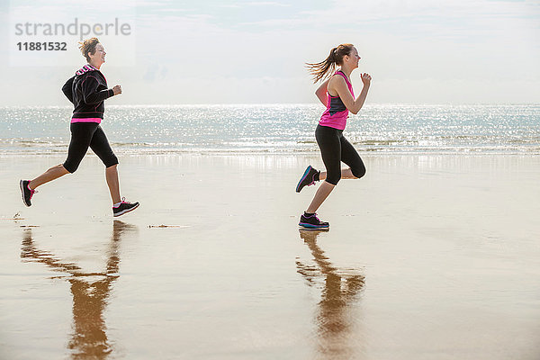 Mutter und Tochter laufen am Strand  Folkestone  UK