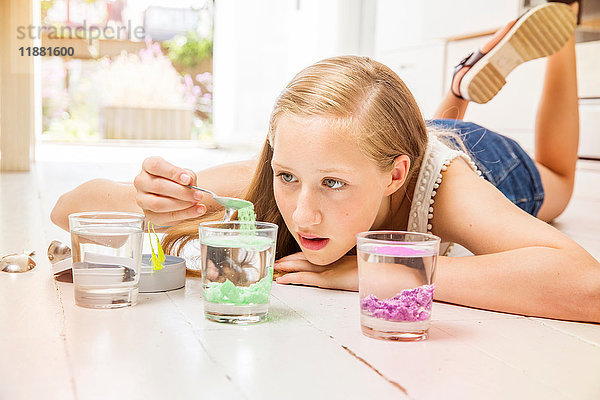 Mädchen liegt auf dem Boden und experimentiert mit Wassergläsern